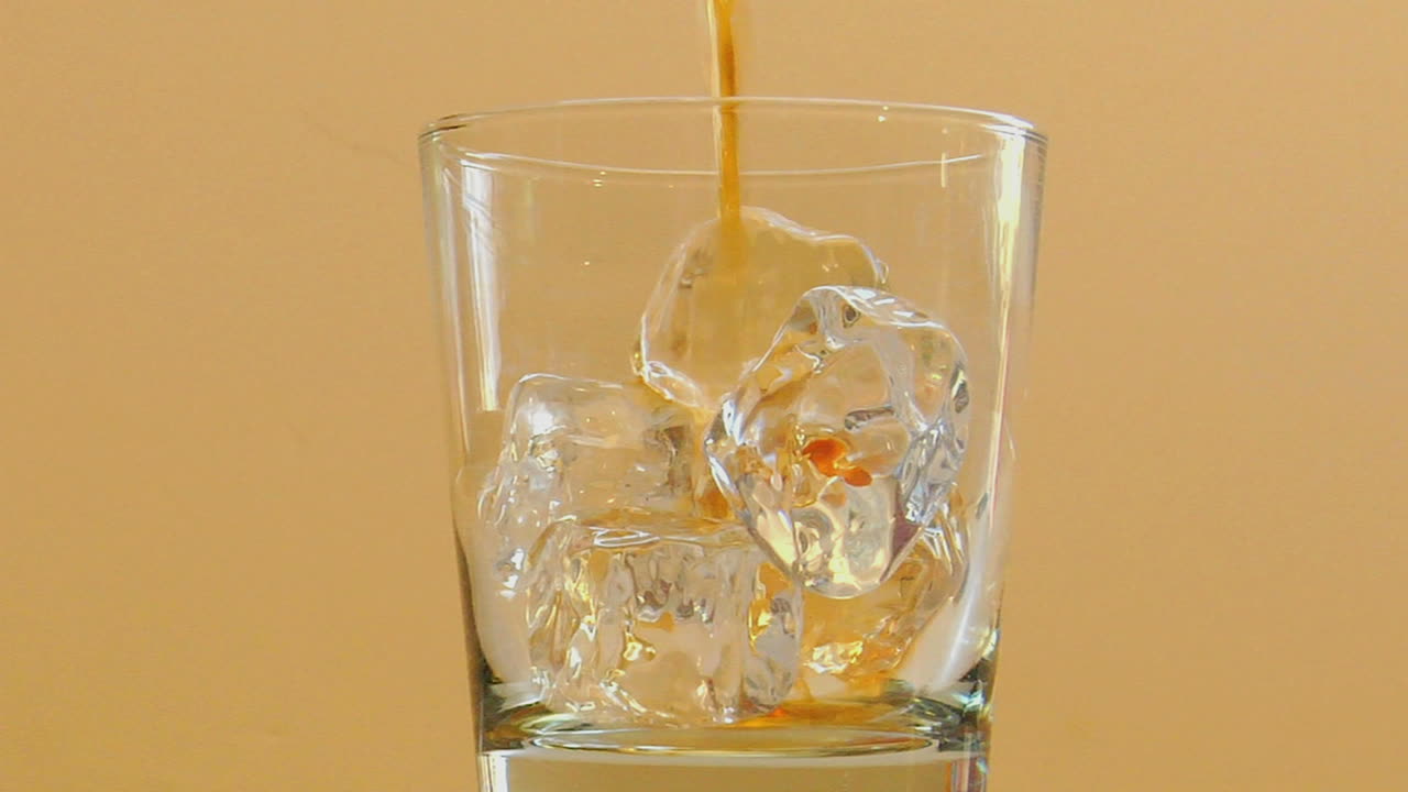 el licor se vierte en un vaso con hielo