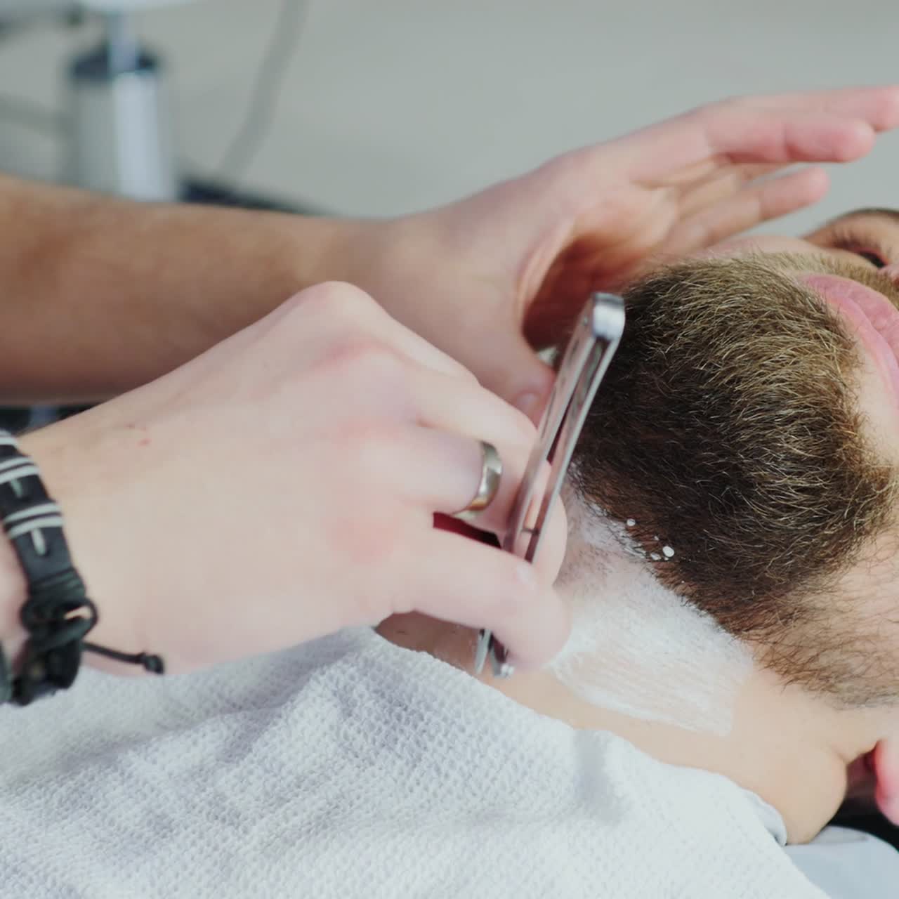 Frisør bruger barberblad på kundens hals