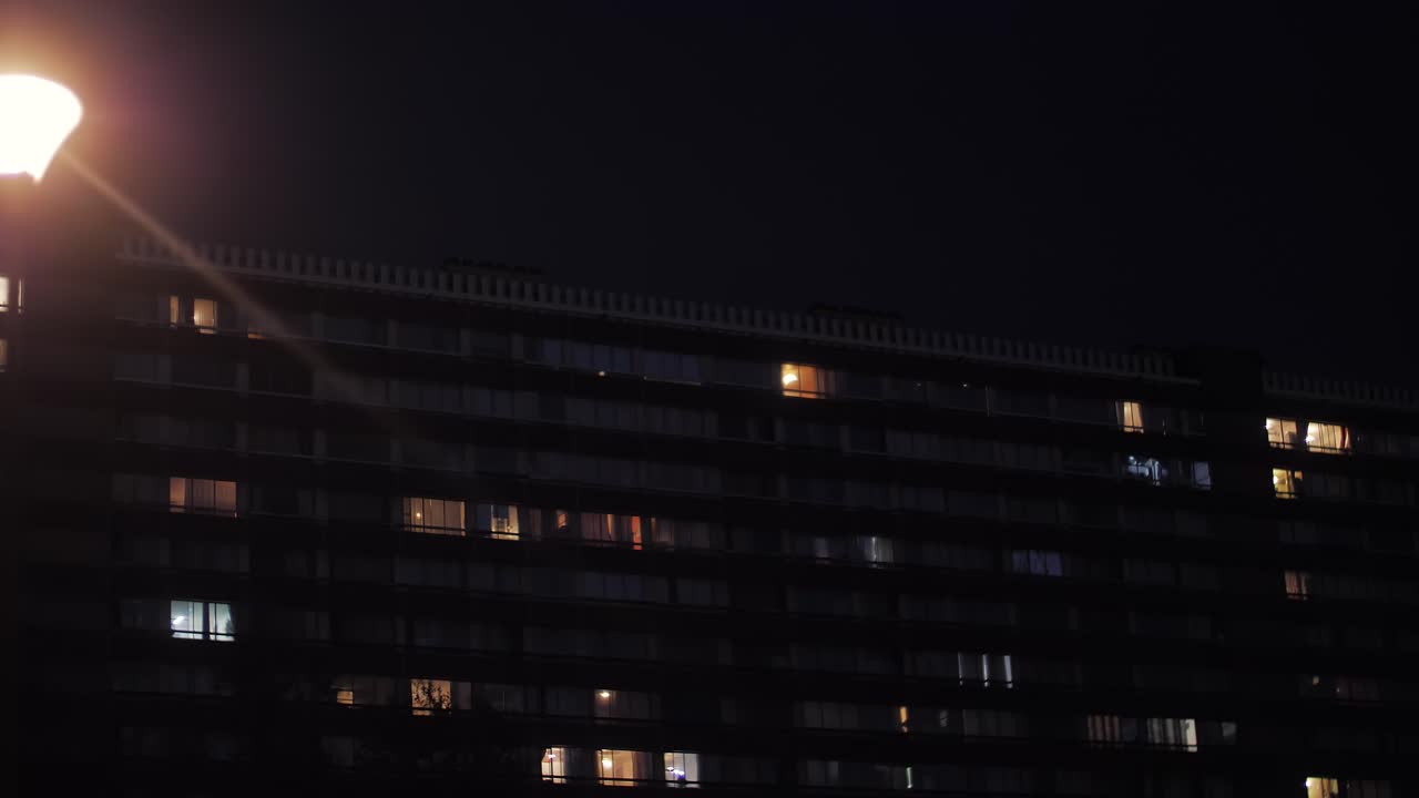 Moving car passing a street light with an old big high-rise residential building in the background