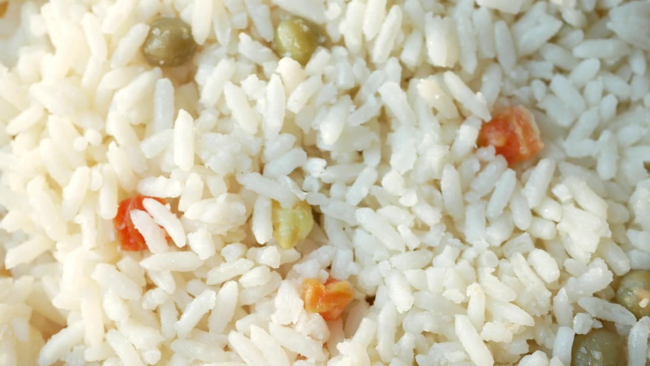 primer plano de un plato de arroz blanco con guisantes y zanahorias
