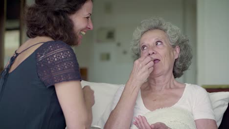 Smiling-senior-woman-taking-pills-in-bed.