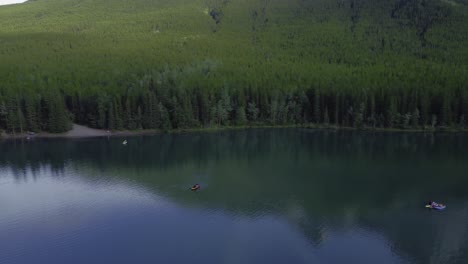 boats on pond in park mountains and forest circling, rockies, kananaskis, alberta canada
