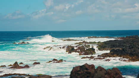 Slow-motion-static-close-up-shot-of-rough-ocean-waves-crushing-against-the-volcanic-rocky-coastline