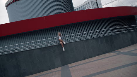 Urban-woman-sitting-building-posing-for-camera-on-city-street.