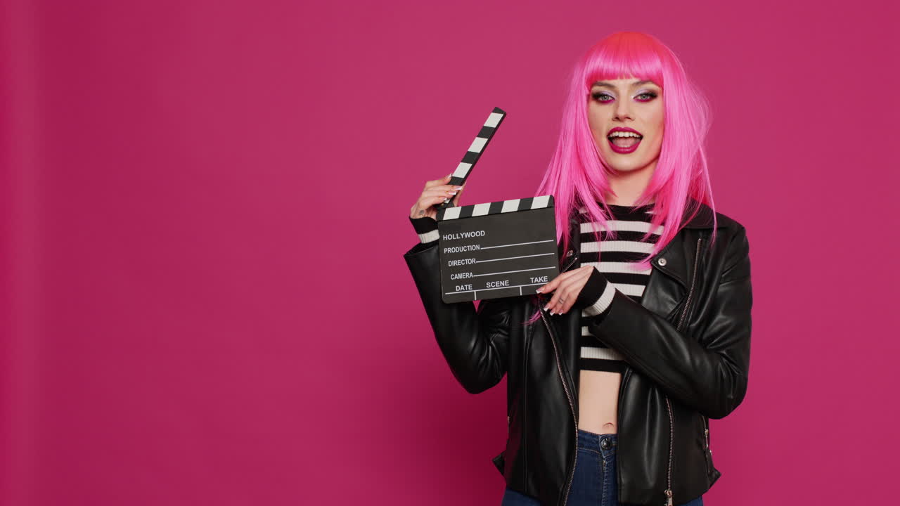 Glamour carefree woman holding film slate and saying action