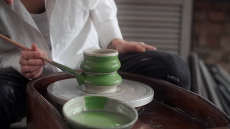 mujer pintando cerámica en una rueda de cerámica