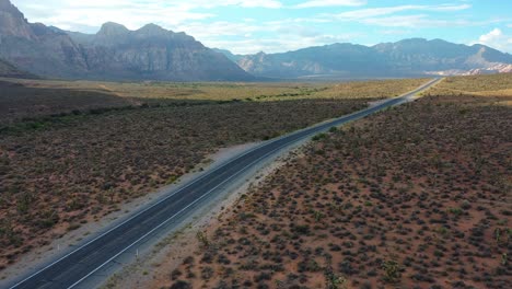 aerial drone shot of an empty road highway with mountains in the background