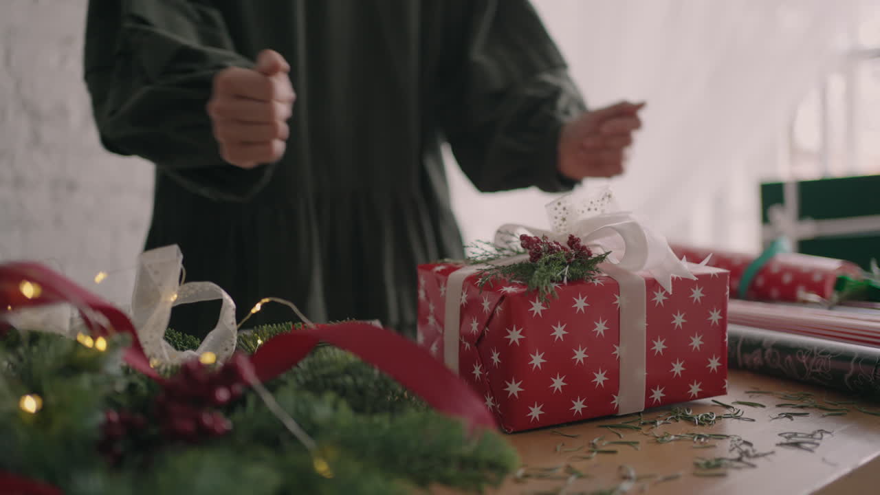 el regalo está listo. el envoltorio de regalo de una joven hermosa mujer envuelve un regalo de navidad y lo decora con adornos decorativos ecológicos. preparación para la temporada navideña.