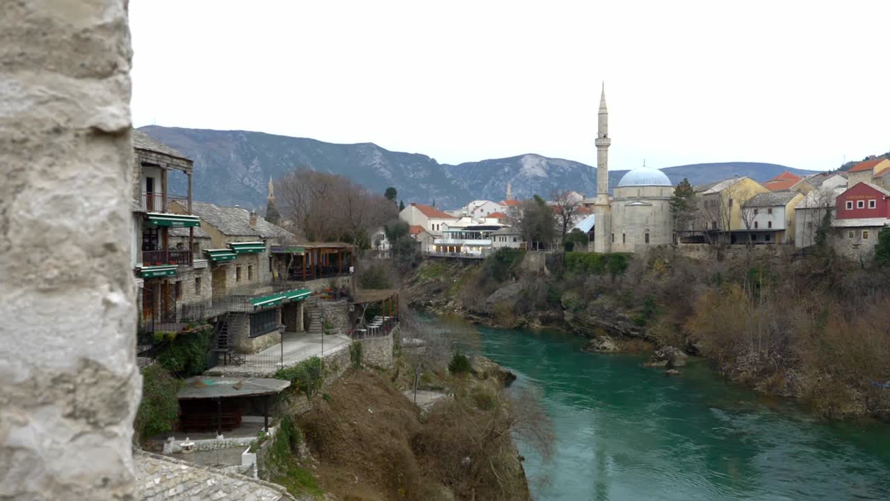 clip con vistas al puente viejo en mostar con vistas al río neretva en un día claro y montañas áridas en el fondo