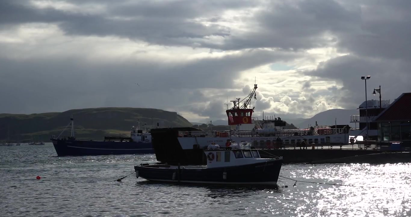 Boats on Oban harbor at sunset behind clouds