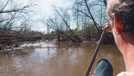 man canoeing on a river in a forest