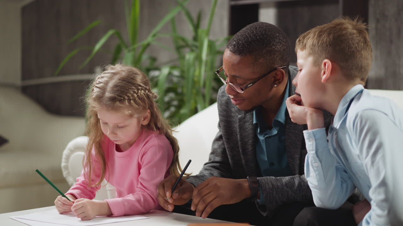 교사 와 소년 은 테이블 에서 편지 를 쓰는 작은 여동생 을 보라