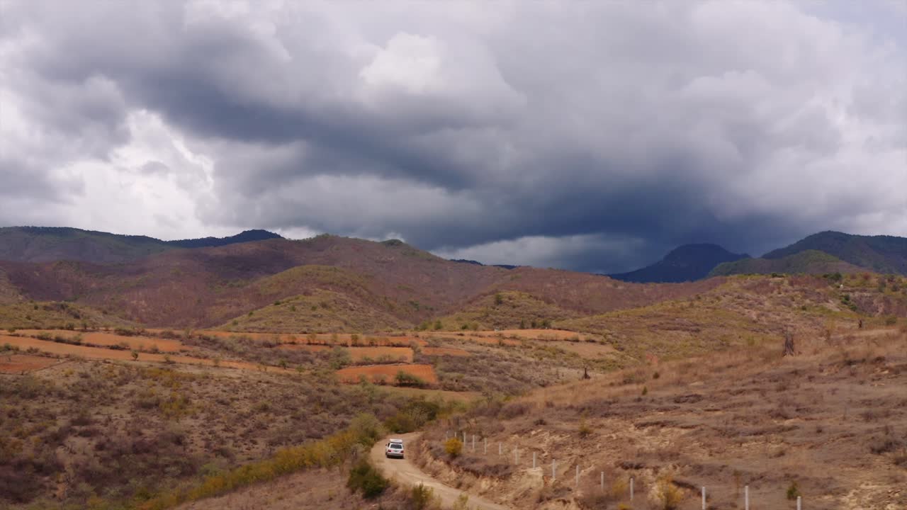 Vista aerea che segue un Landcruiser con tenda da tetto mentre si dirige verso le tempestose montagne di Oaxaca, Messico.