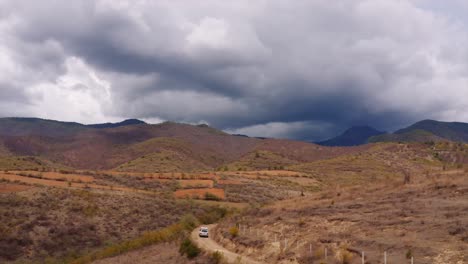 vista aérea siguiendo un landcruiser con tienda en el techo conduciendo hacia las tormentosas montañas de oaxaca, méxico