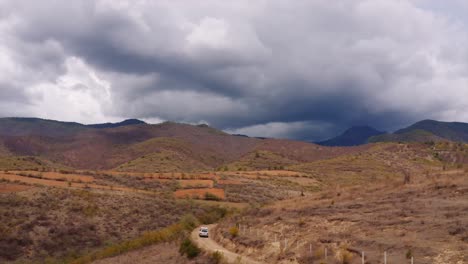 aerial view following landcruiser with rooftop tent driving towards stormy oaxaca mountains, mexico