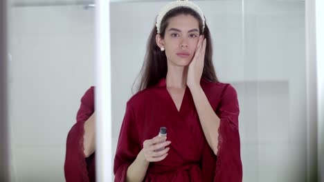 una mujer hermosa que emplea corrector para cubrir imperfecciones minúsculas.