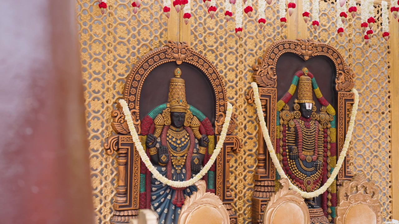 Camera slides to reveal ornate Hindu wedding mantap decor with deity panels outdoors