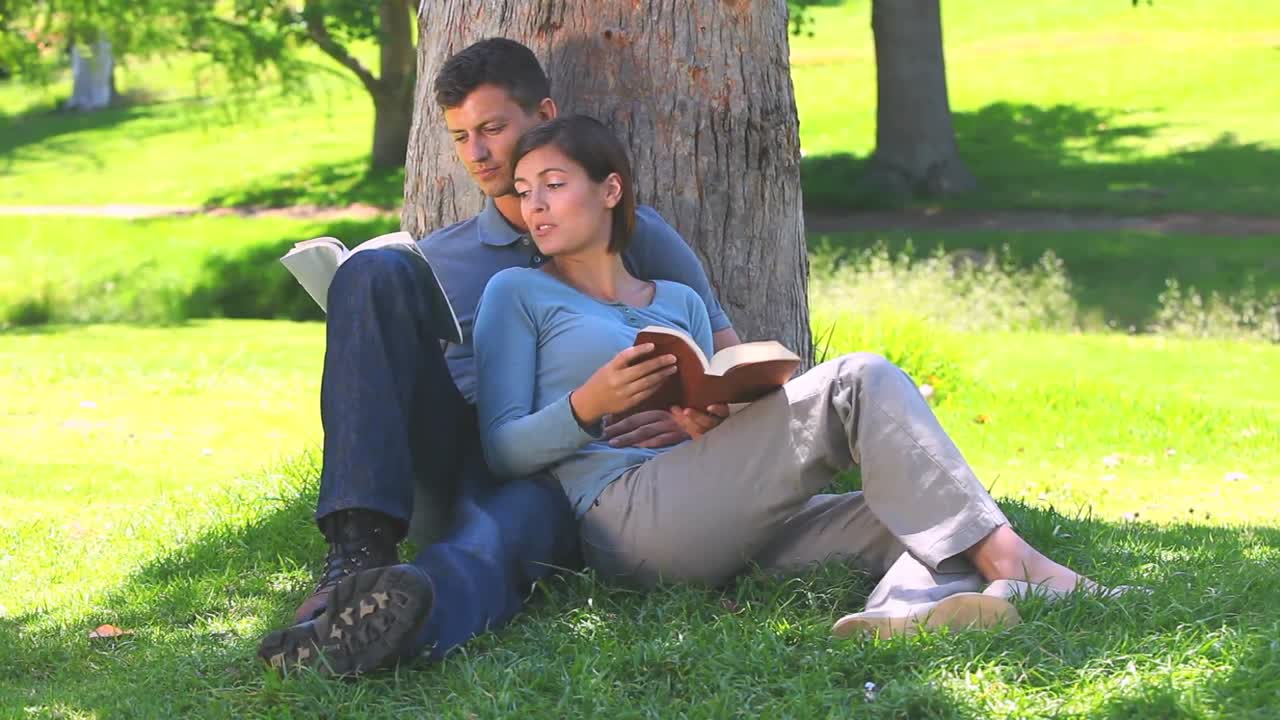 Young couple reading book outdoors