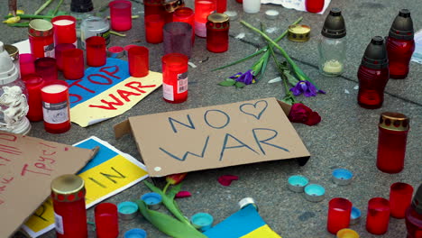 antiwar sign, ukrainian flags and candles on the pavement at a protest