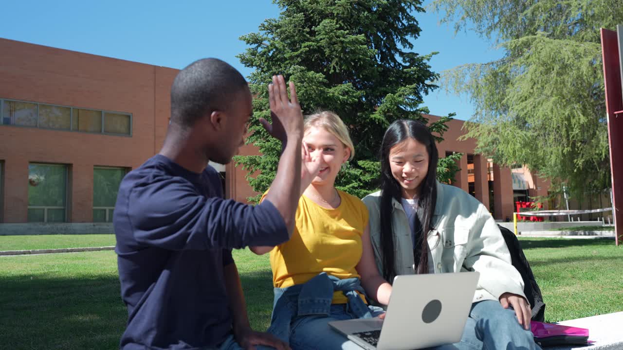 Students collaborating on a laptop outdoors