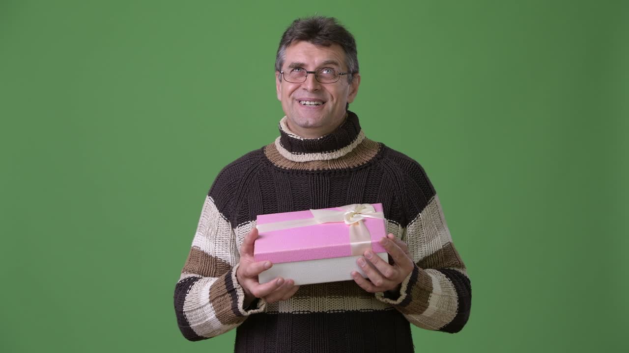 초록색 배경 에 털 목 스웨터 를 입은 성숙 한 잘생긴 남자