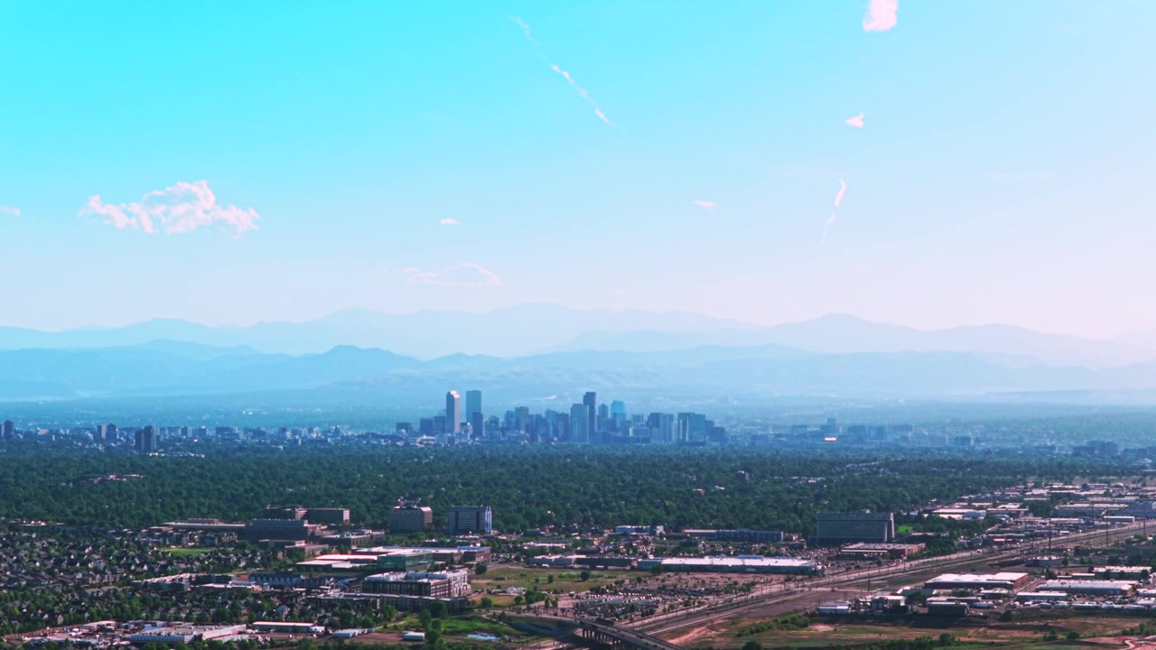 Città di Denver, centro: grattacieli, edifici, paesaggio urbano, vista aerea con drone. Colorado, auto, traffico, colline pedemontane del Front Range delle Montagne Rocciose a strati. Estate, primavera, cieli blu, foschia mattutina, nuvole in primo piano.