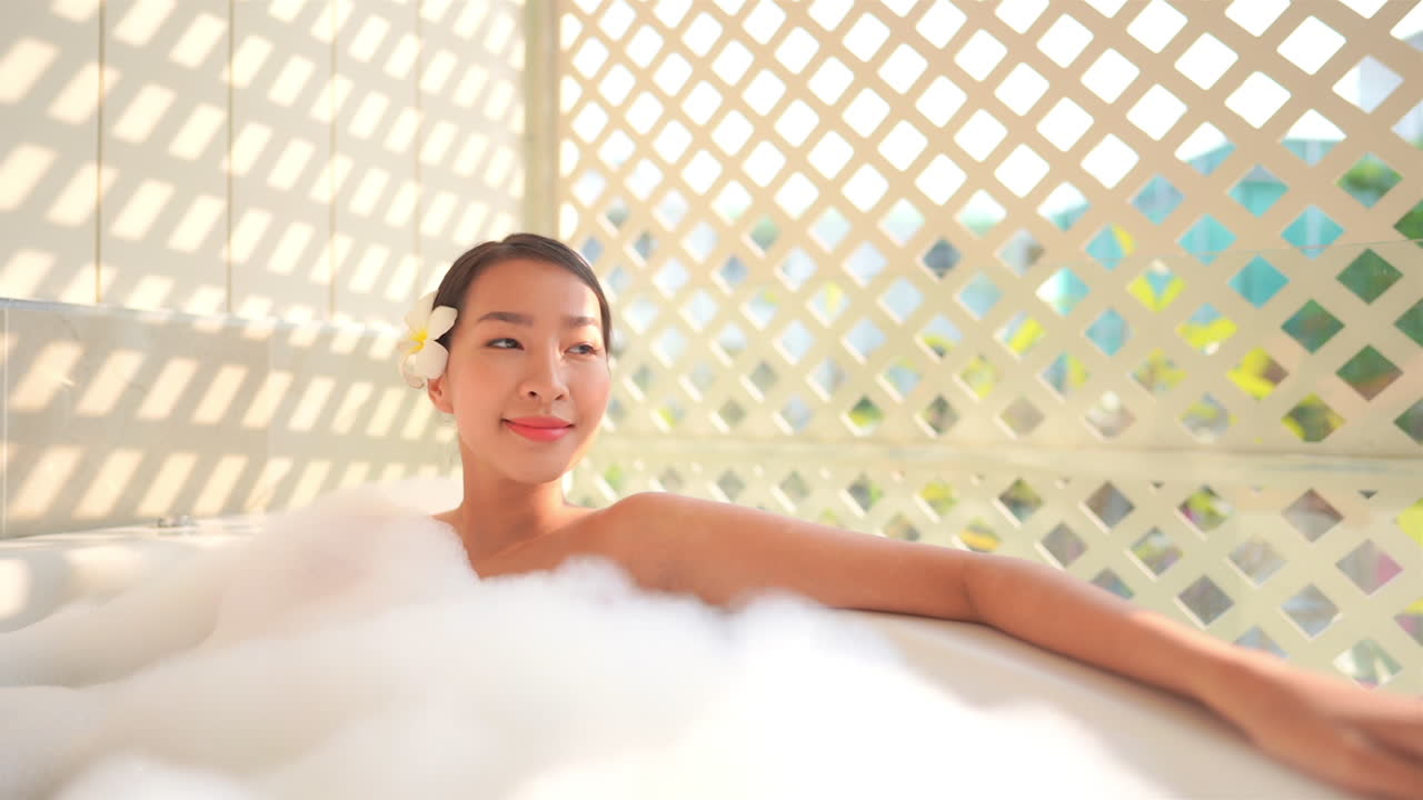 A young Asian woman relaxes in a tub full of bubbles