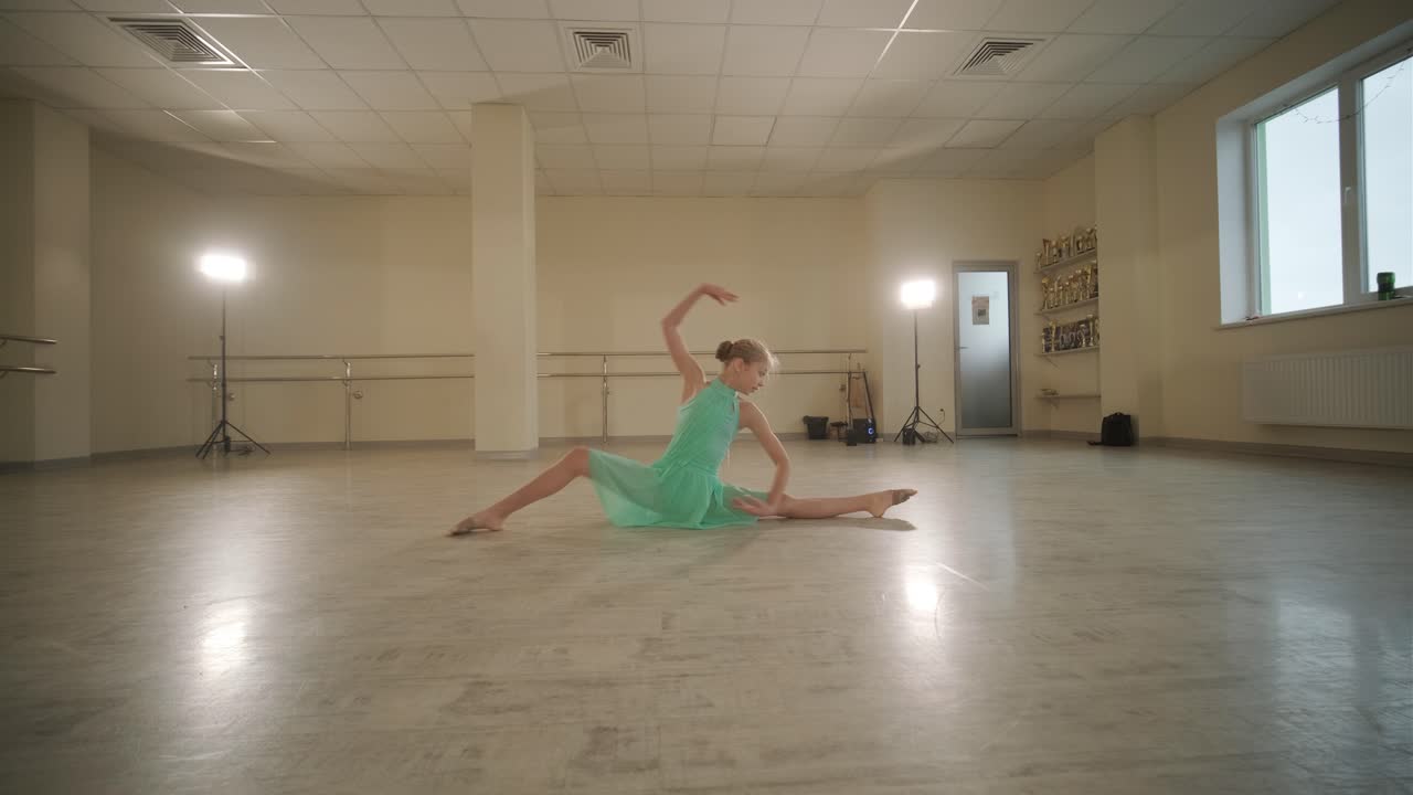 Un gruppo di giovani allievi di danza classica in abbigliamento da ballo nero che eseguono esercizi in un ampio studio di danza con pavimenti in legno e barre a muro. Espressioni concentrate e movimenti sincronizzati