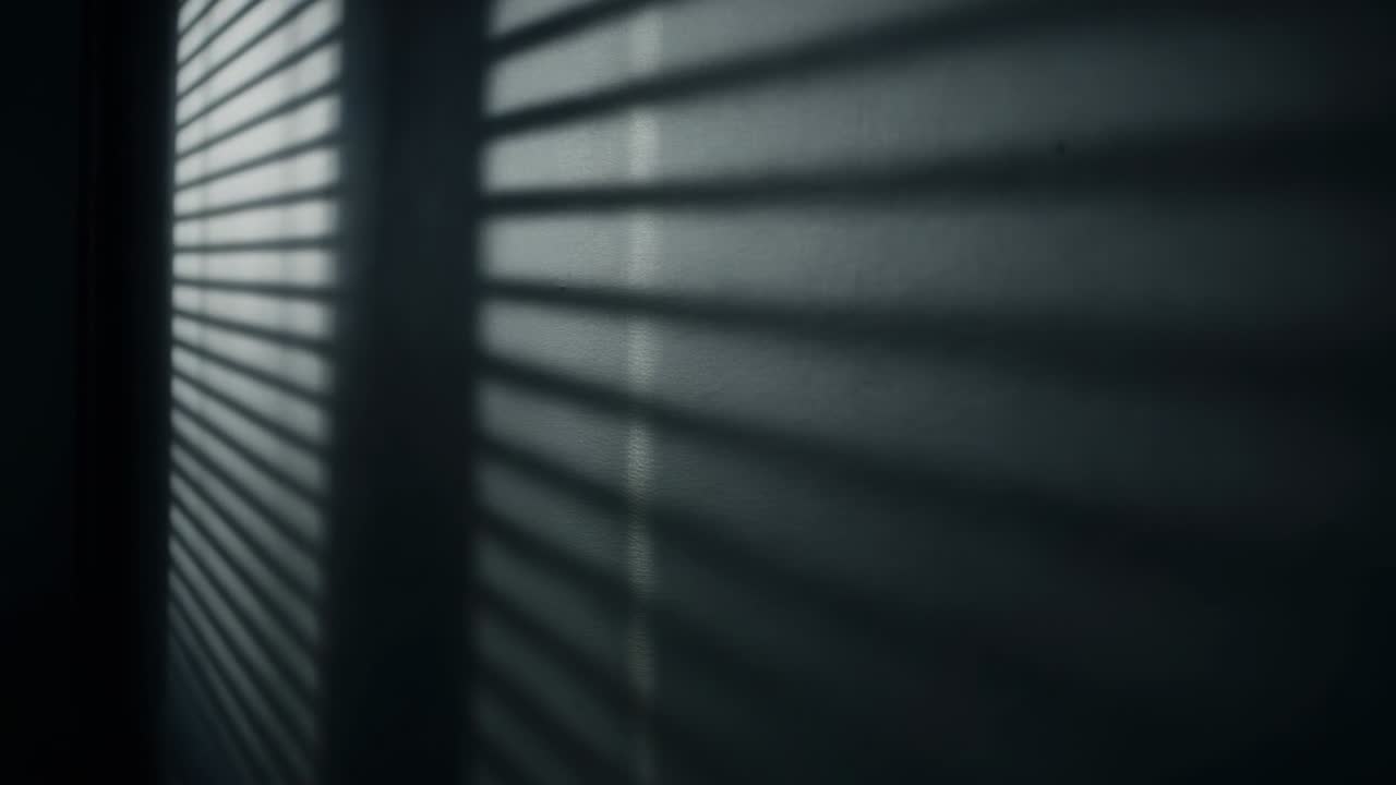 Panning camera revealing striped shadow sweeping across painted wall by blinds, exposing texture
