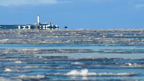 el hielo derretido fluye por un río soleado en invierno con un faro, tiro largo