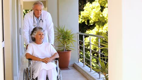 doctor taking a woman in weelchair for a walk