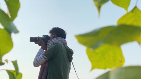 portrait of south asian young man taking photos of nature, leaf in front of lens