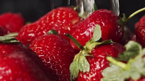 water droplets splashing onto red strawberries macro closeup