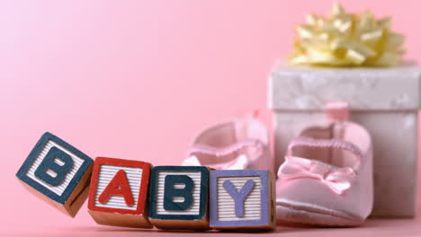 baby blocks toppling over in front of booties and gift box