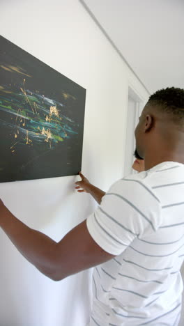vertical video: admiring abstract painting, man in striped shirt appreciating art at home
