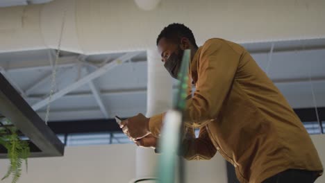 Video-De-Un-Hombre-De-Negocios-Afroamericano-Con-Mascarilla-Usando-Un-Teléfono-Inteligente-En-Las-Escaleras-De-La-Oficina