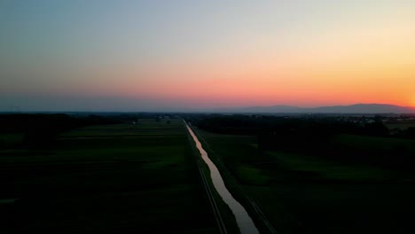aerial panoramic view of calm river and fields at sunset - drone shot