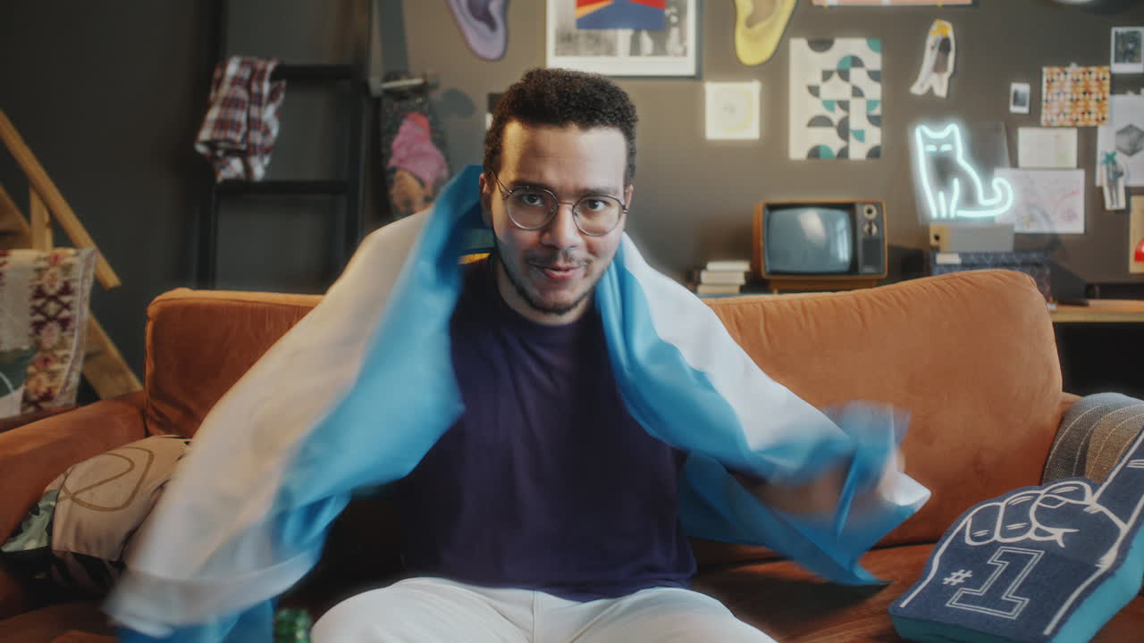 Excited Sports Fan Watching TV Game at Home with Argentine Flag