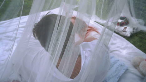 man and red hair woman laying on white veil behind transparent cloth at park