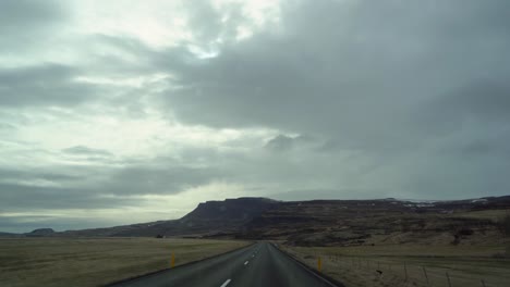 Bewölkter-Himmel-über-Einer-Leeren-Isländischen-Straße,-Fahrerperspektive,-Dramatische-Landschaft