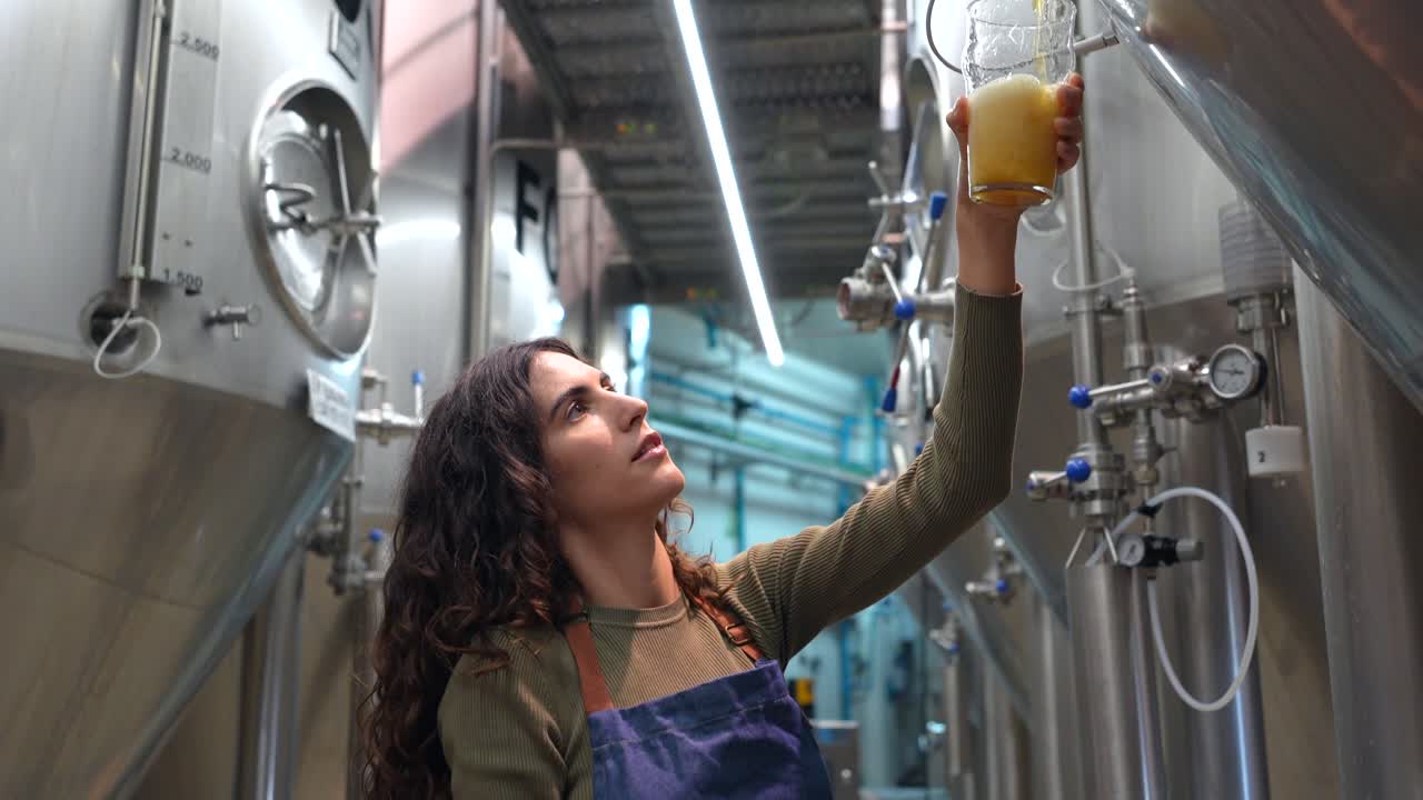 A woman working at a brewery samples the beer