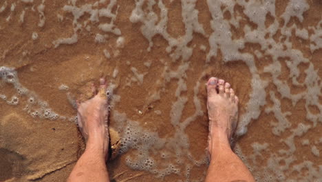 feet being cooled of by incoming waves at shore