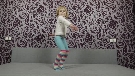 niño feliz saltando y bailando en el sofá y escuchando música