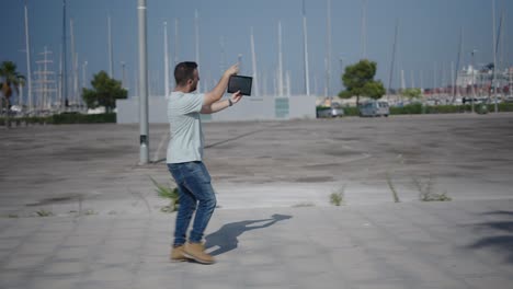 man walking and holding tablet in a city park