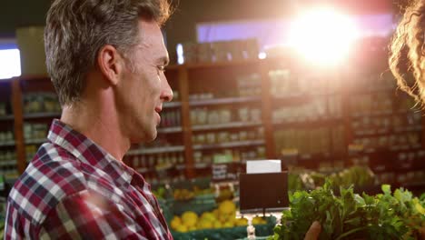 happy couple buying vegetables in organic section of supermarket