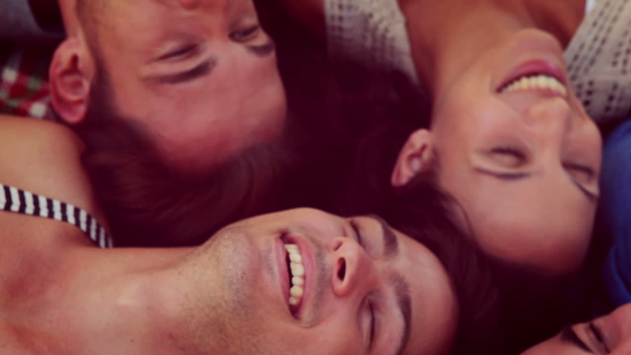 Happy friends lying on blanket in the park