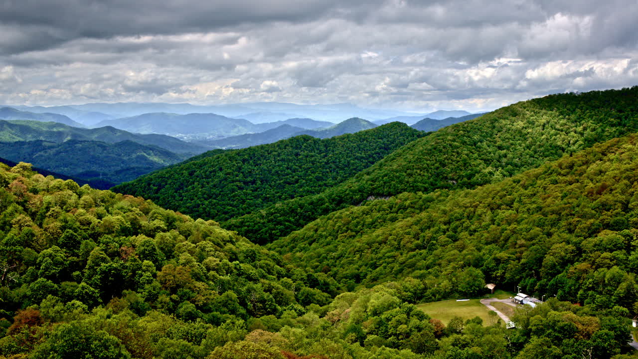 Drone glides through smoky clouds above rain-kissed mountains