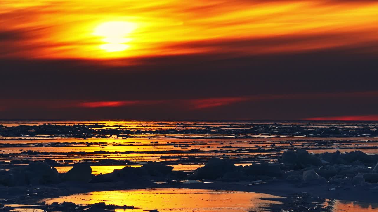 Gelo marinho ártico refletindo cores dramáticas do pôr do sol, ambiente de clima frio com blocos de gelo.