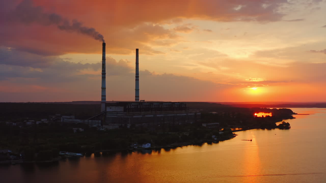 Industrial factory. Smoke comes from the chimneys of the factory, polluting the atmosphere. Video from drone on beautiful sunset.