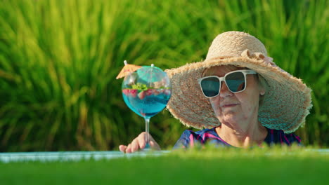 senior woman enjoying a cocktail by the pool